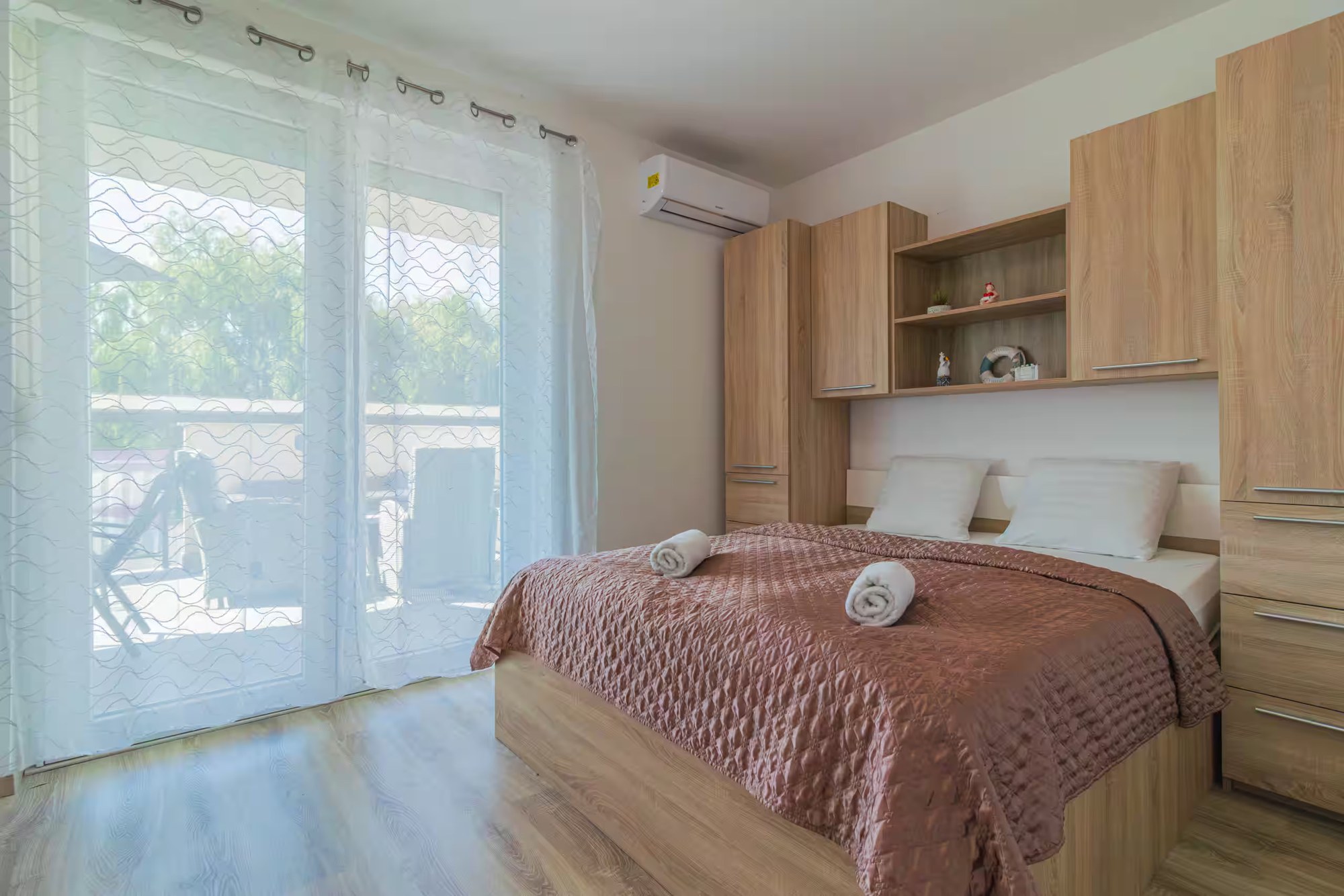 Schlafzimmer mit Doppelbett und großen Glastüren zur Terrasse