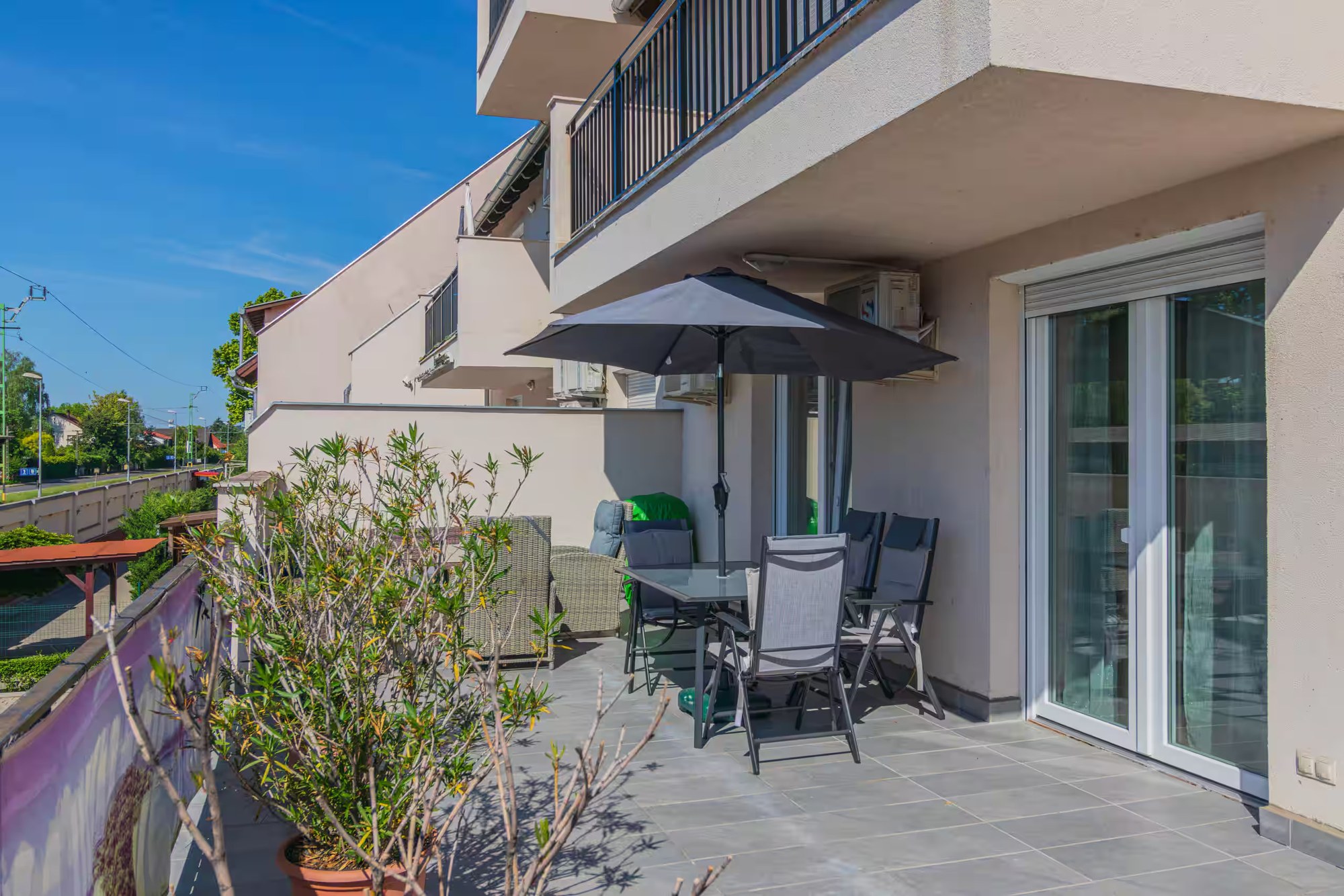 Terrasse der Wohnung mit Gartentisch, Sonnenschirm und Pflanzen